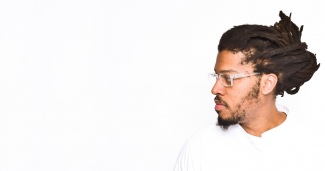 Side profile of Kamau Ware, wearing a white shirt, looking to the right toward a vast, empty white space.